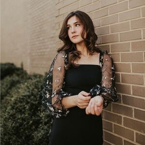 Black knee-length dress with embroidered sleeves.